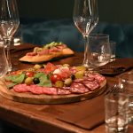 Sophisticated charcuterie board with wine glasses on a wooden table creates a cozy dining ambiance.