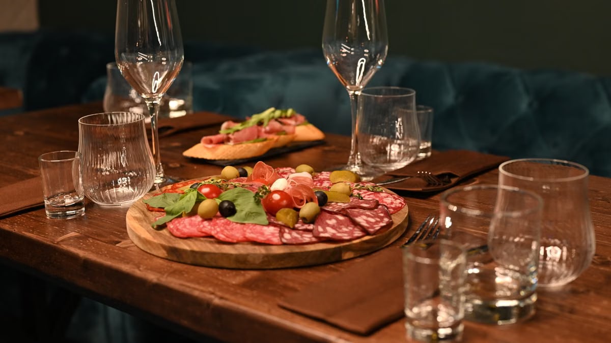 Sophisticated charcuterie board with wine glasses on a wooden table creates a cozy dining ambiance.